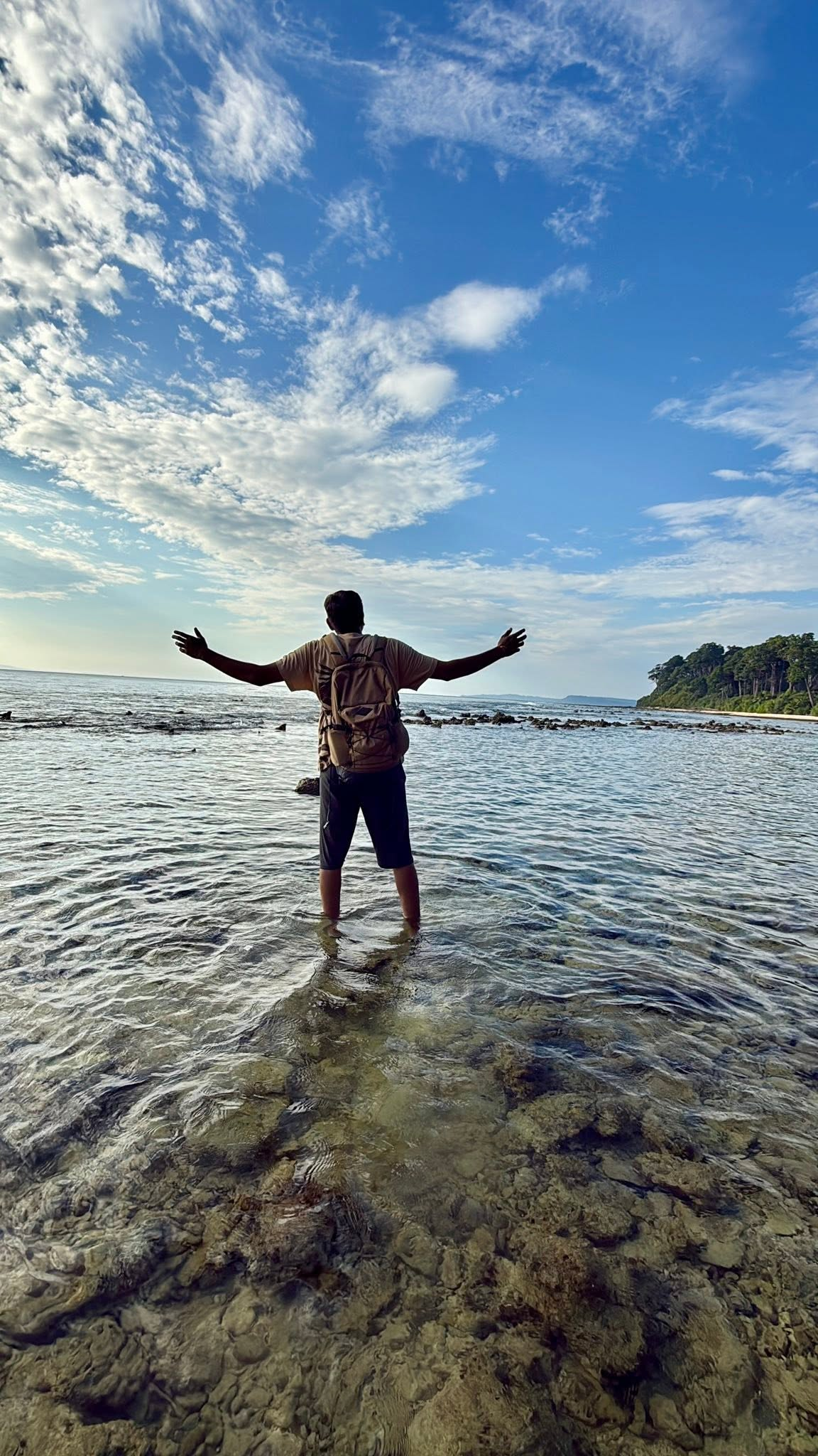 Chetan standing in the sea beneath a wide blue sky